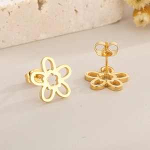 Macro view of gold flower earrings with hollow petal design on stone surface