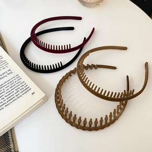 Detail view of four non-slip velvet headbands in assorted colors on a minimalist desk