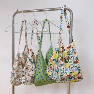 Close-up of four floral cotton tote bags hanging on a rack showing different prints