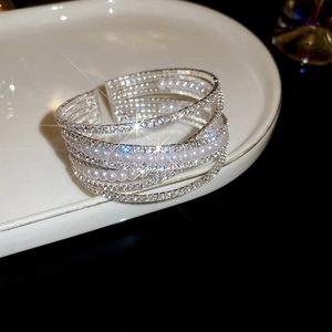 Detail of silver-tone multi-layer bracelet with sparkling rhinestones and white pearls