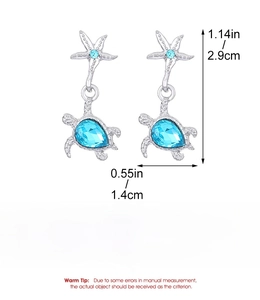 Detailed macro view of silver alloy starfish and turtle earrings with blue gemstones