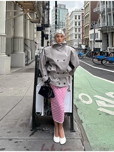 Detail of grey double-breasted trench coat paired with pink polka dot dress and headscarf