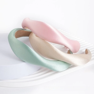 Close-up of thick satin sponge headbands in pink, light green, and champagne colors