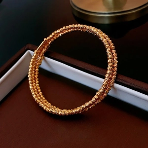 Elegant gold spiral bracelet with triple layer bead chain texture on a jewelry box