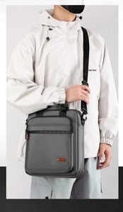 Vertical grey crossbody bag with multiple zipper pockets and adjustable shoulder strap