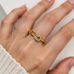 Detail of 18K gold plated safety pin ring with pavé zircons on woman's index finger