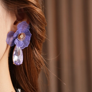 Detailed close-up of a model wearing purple floral crystal teardrop earrings