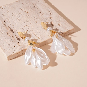 Gros plan détaillé de boucles d'oreilles pétales avec résine blanche, perles et doré