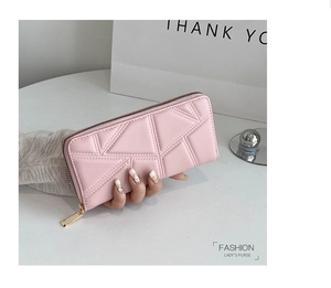 Detail of pink long wallet featuring geometric quilted texture and gold zipper closure
