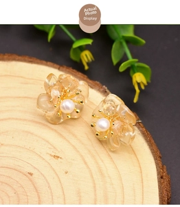 Detailed close-up of floral resin earrings with white pearl center on natural wood