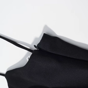 Detail of invisible side zipper and fine texture on a black polka dot strap dress