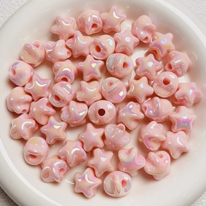 Close-up of pink iridescent star beads in a ceramic bowl for DIY jewelry making