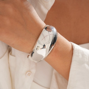 Detail of wide polished silver open cuff bracelet with high mirror finish on model's wrist
