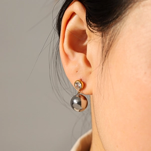 Two-tone sphere earrings featuring a gold stud with zircon and silver polished metal ball
