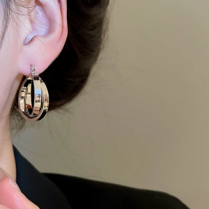 Detail view of silver twisted hoop earrings on a model showing polished metal texture