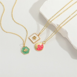 Three gold necklaces with green bee, white flower, and pink moon sun pendants on white stone