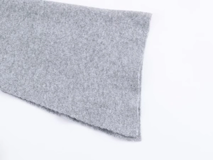 Macro shot of light gray thick knitted fabric showing soft wool texture and cuff detail