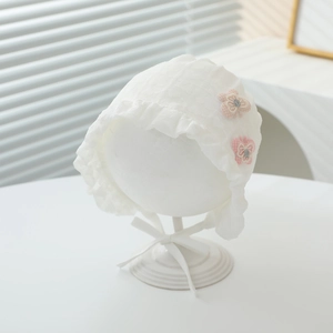 Detail of baby lace bonnet featuring pink bow accents and delicate ruffled edges