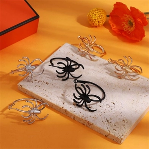 Gothic spider hoop earrings in black, gold, and silver on an orange background