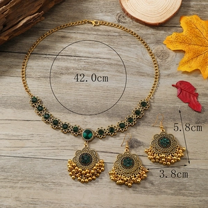 Vintage gold jewelry set with green gemstones, flower patterns and golden tassels