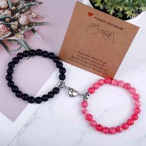 Detailed view of magnetic heart charm connecting black and red natural stone bracelets