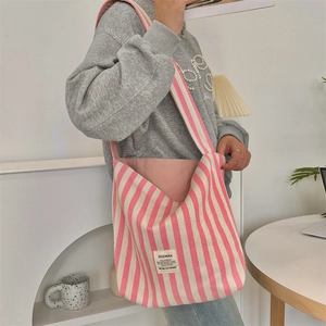 Dettaglio della borsa tote in tela a righe bianche e rosa con etichetta logo in tessuto