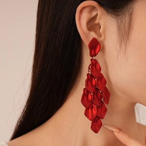 Close-up of elegant red acrylic rose petal tassel earrings worn by a model in profile
