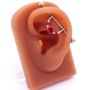 Orecchino industrial barbell con rosa rossa e cristalli su modello di orecchio