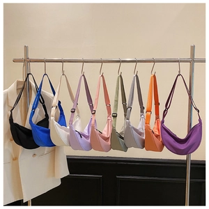 Macro display of nine colorful nylon crescent bags hanging on metal hooks in a row