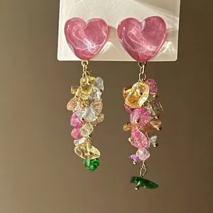 Detail of pink heart stud earrings with dangling colorful irregular stone tassels