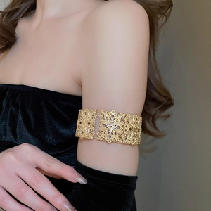 Détail du bracelet de bras doré avec motif de fleurs sur le bras d'un mannequin en noir