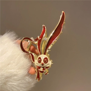 Detail of golden rabbit hair claw clip with red and white enamel floral accents