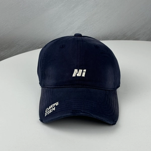 Close-up of embroidered white Ni letter and distressed details on a navy baseball cap