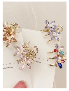 Close-up of small floral crystal hair claws with rhinestones on a display card
