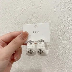 Detail view of white plush hoop earrings featuring silver cross charms and S925 silver studs
