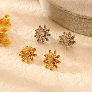 Detailed view of layered daisy flower stud earrings in gold and silver plated finishes
