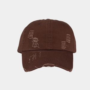 Close-up of distressed ripped details on a dark brown washed cotton baseball cap