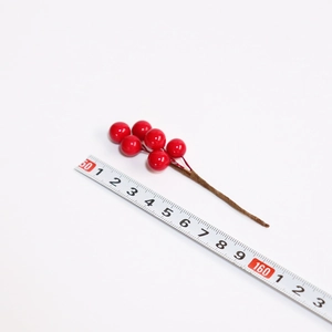 Detailed view of artificial red berry branch with scale ruler showing 12-14cm length