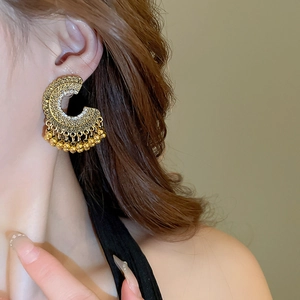 Detail of bohemian gold hollow drop earrings with pearl tassels on female model