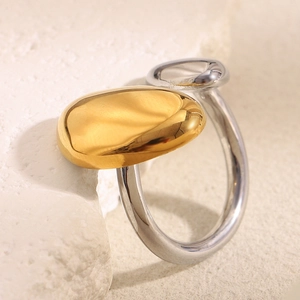 Detail of two-tone gold and silver stainless steel irregular ring on stone base