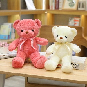 Ositos de peluche coral y crema sentados en un escritorio con cintas decorativas