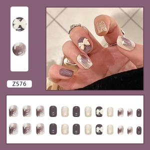 Faux ongles graffiti violets avec nœuds 3D blancs et paillettes dorées champagne