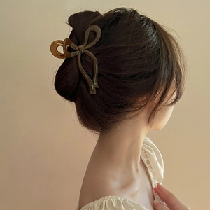 Detail view of a dark brown bow hair claw clip styled on a low bun hair arrangement