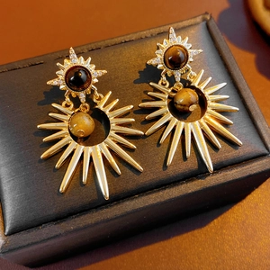 Detail view of retro sunburst earrings with tiger eye stone and zircon on a black box
