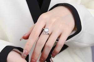 Close-up of rotatable silver ring with shell surface and zircons on model finger