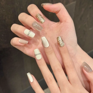 Close-up of champagne cat-eye press-on nails with glitter and metallic stripe details