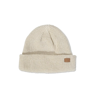 Detailed texture of beige knit beanie featuring a brown leather patch on the folded brim