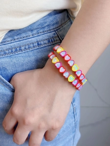 Close-up detail of colorful heart enamel stackable elastic bracelets worn on a female wrist