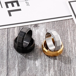 Close-up of 8mm brushed stainless steel rings with geometric faceted edges on a grey surface