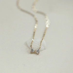 Elegant 14k gold plated bow necklace featuring two heart-shaped crystal pendants